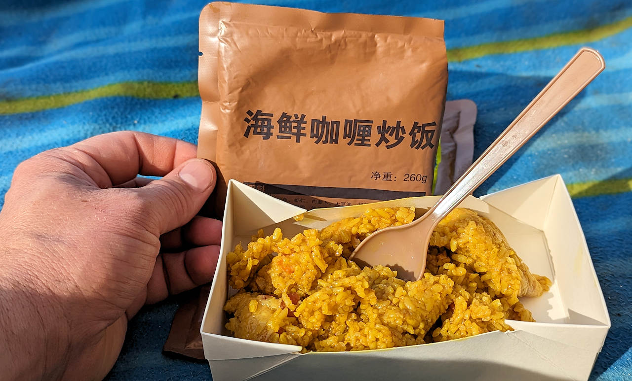 Inhalt von einem chinesischen MRE. Eine Portion Meeresfrüchte mit Curry Reis in einer kleinen Schale mit Löffel. 