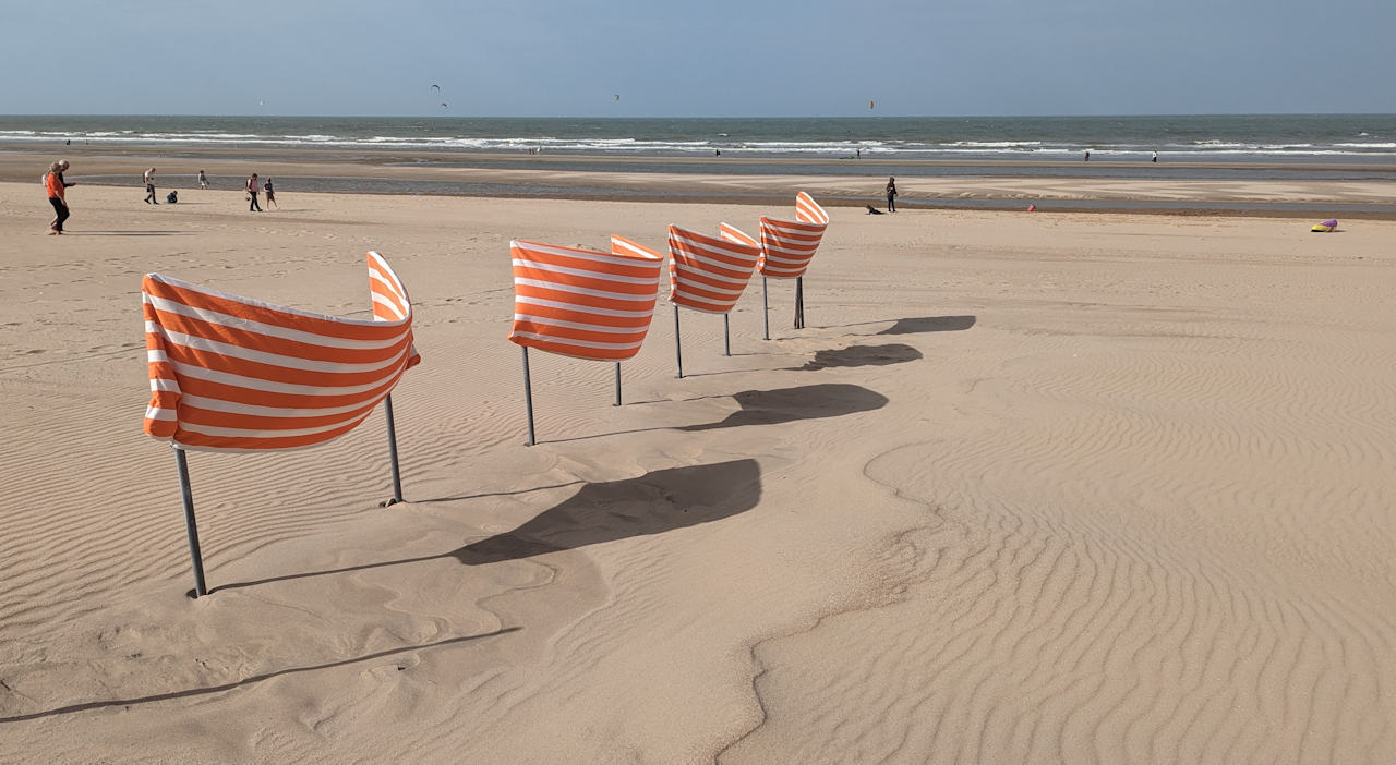 Vier orange weisse Fahnen am Strand von De Haan