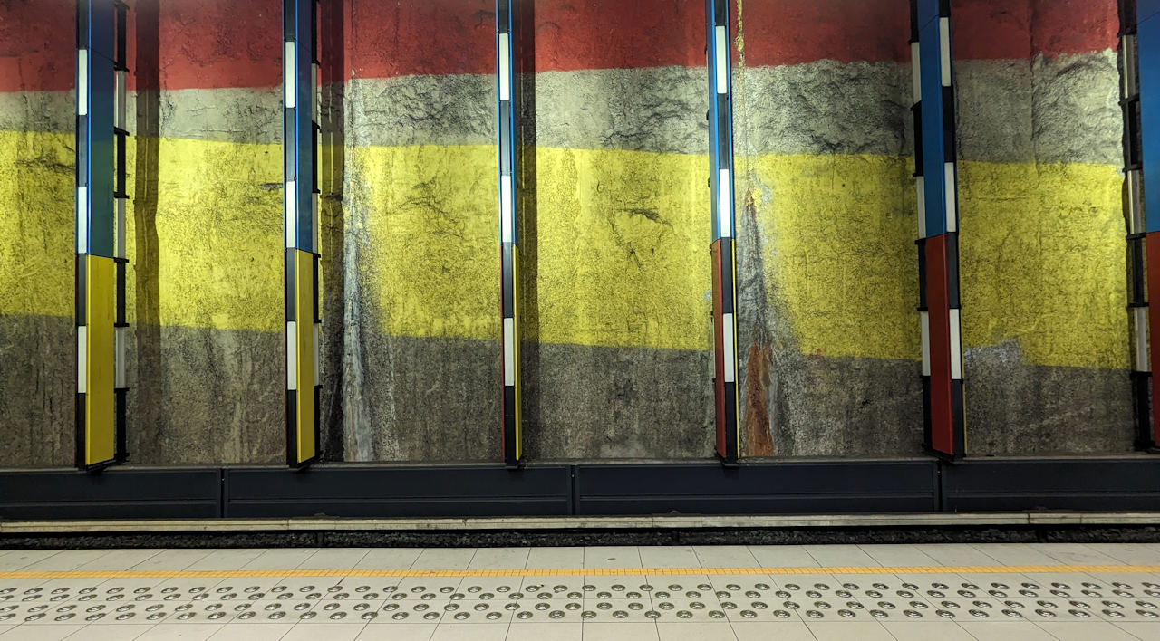 Wand der Metro Station Bockstael Brüssel mit gelben und roten Farbstreifen hinter Metall Stelen