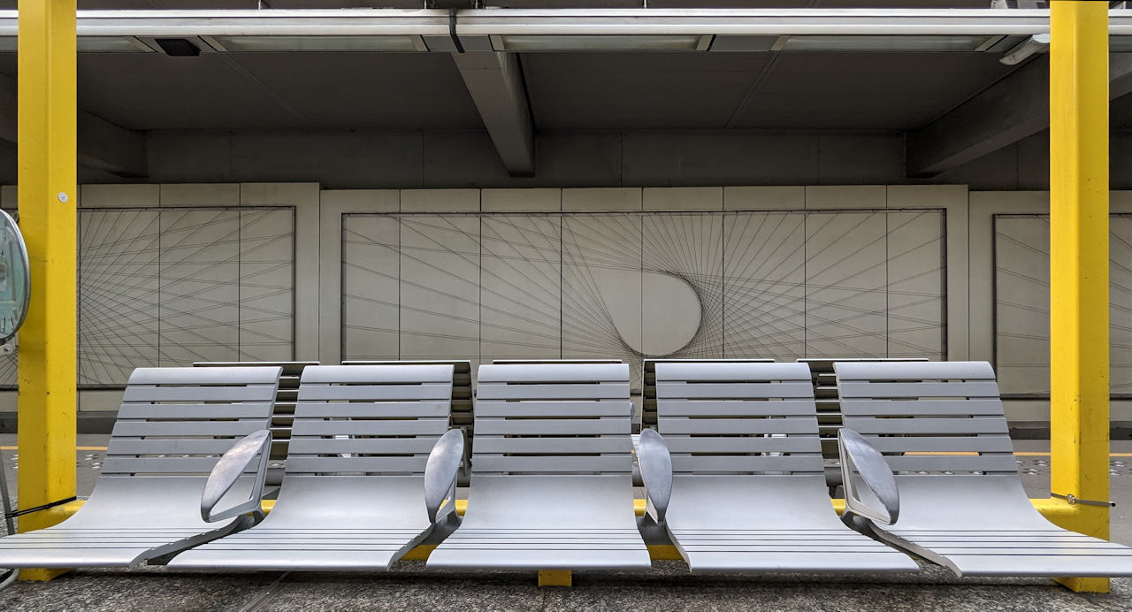 Sitzbank der Metro Station Delacroix in Brüssel mit Drahtgrafik im Hintergrund.