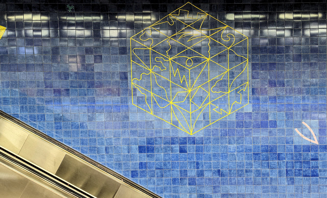 Blaue kacheln mit gelbem Drahtwürfel in der Metro Station Tomberg Brüssel