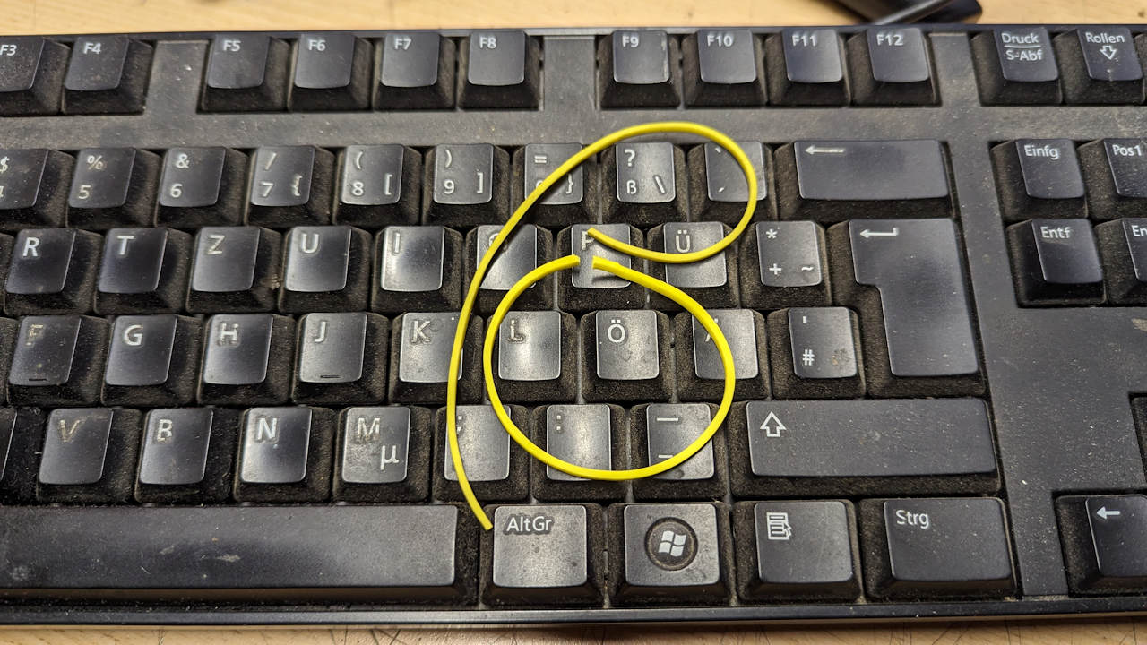 Zerrissene gelbe Gummibänder formen auf einer schwarzen Tastatur den Buchstaben ß