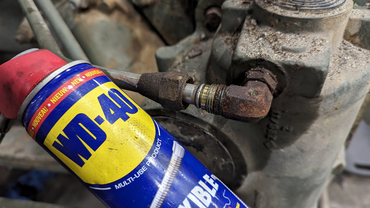 Eine Dose WD40 Spray vor einem rostigen Gewinde mit Überwurfmutter