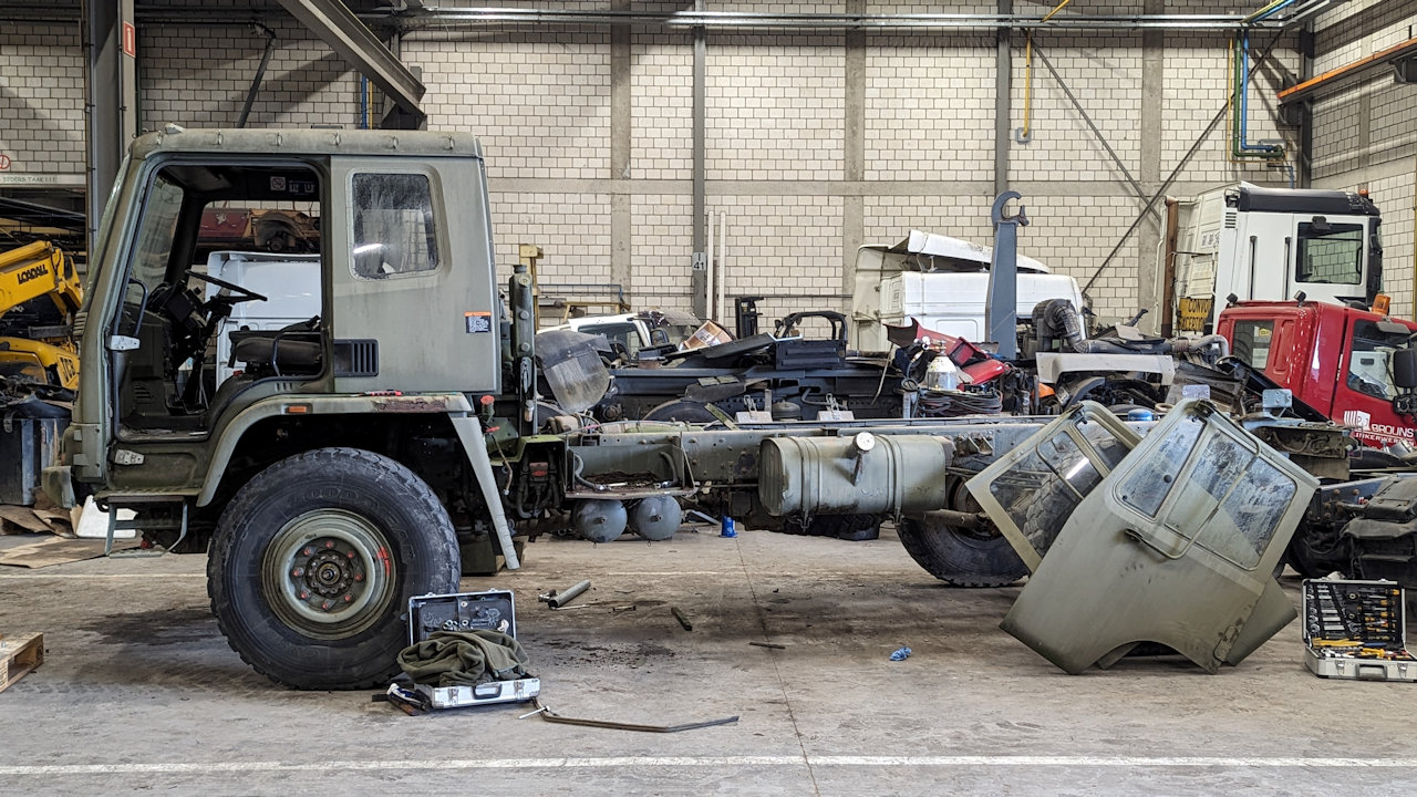 Ein olivgrüner Militär LKW steht mit abgebauter Ladepritsche in einer Halle