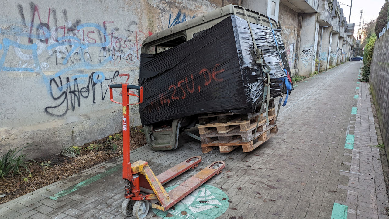 Eine gekippte Paletten mit einem in schwarzer Folie verpackten LKW Führerhaus steh havariert auf einem Fahrradweg