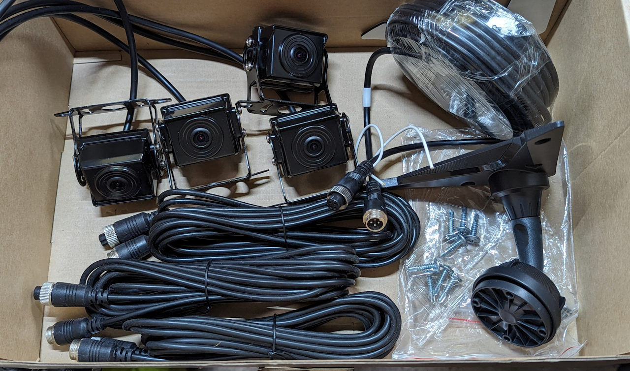 Karton Inhalt einer 10.36 Rückfahrkamera, bestehend aus vier Kameras, vier Kabel und einer schwarzen Kunststoff Halterung