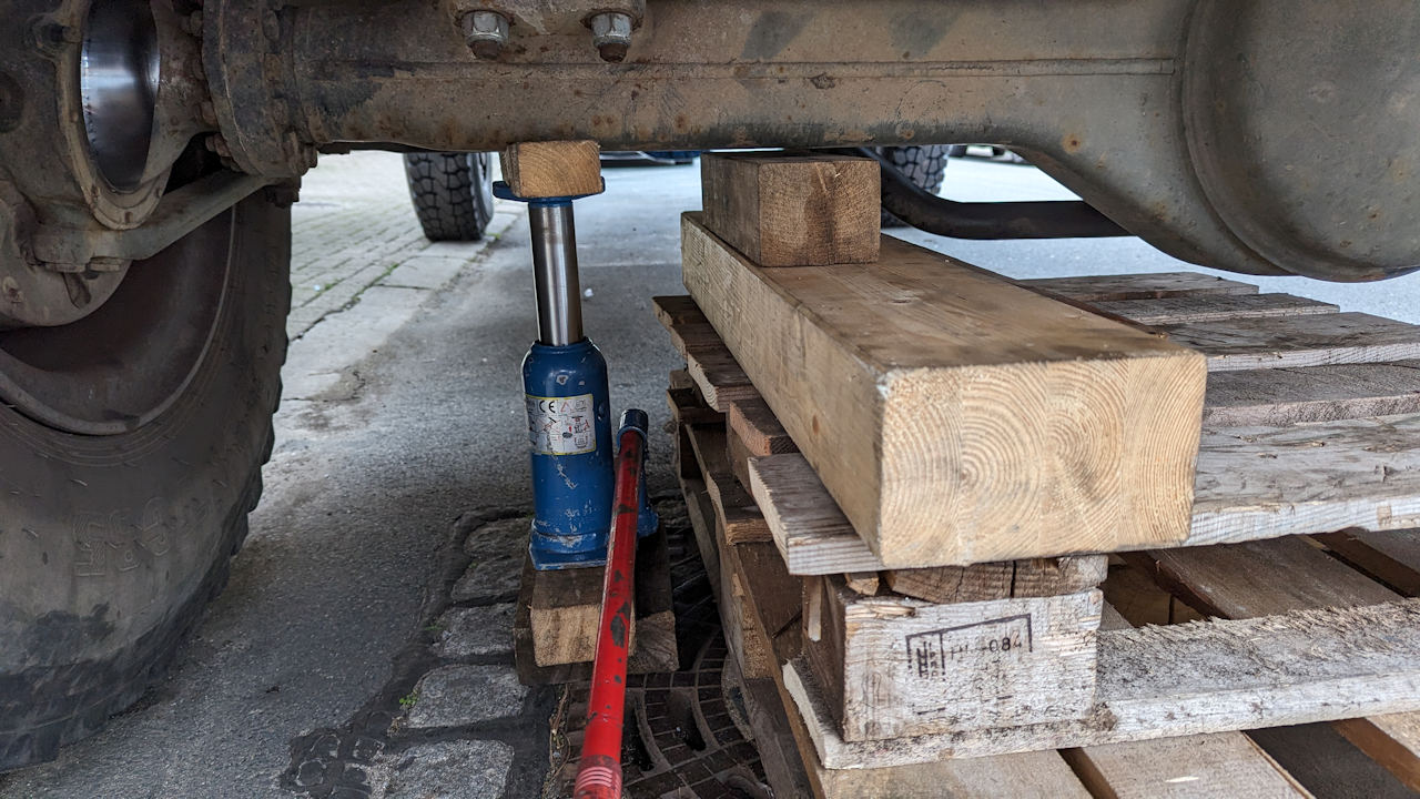 Wagenheber unter einer LKW Achse mit zusätzlicher Absicherung durch Holz Paletten