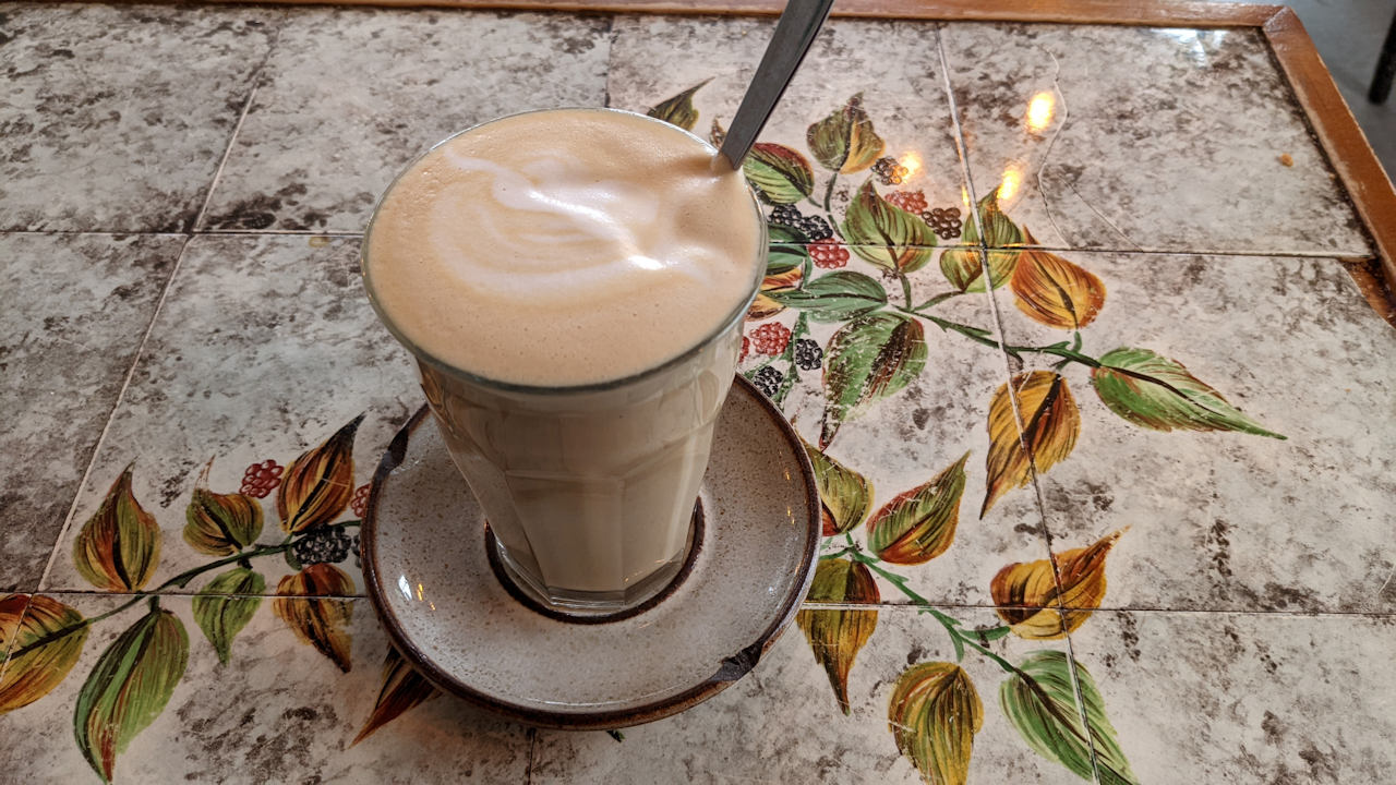 Glas Milchkaffee auf einem Tisch mit Brombeeren Blumen Muster