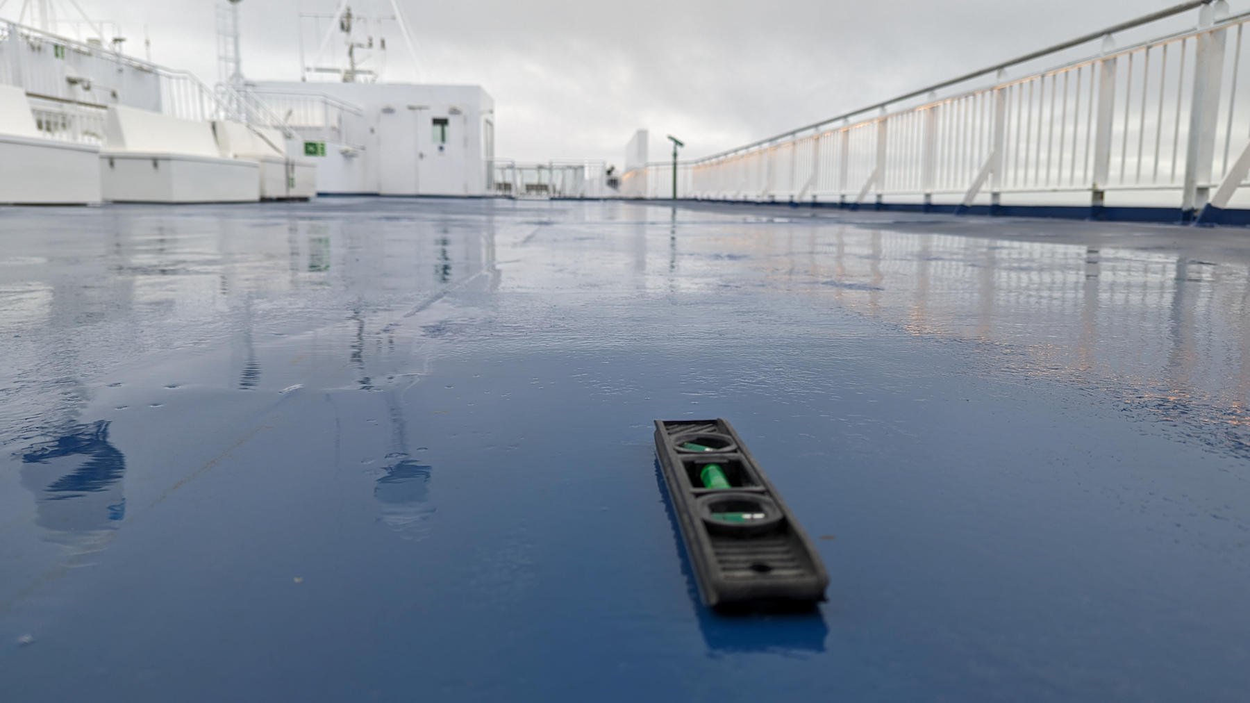 Schwarze Wasserwaage liegt auf einem blauen Schiffsdeck