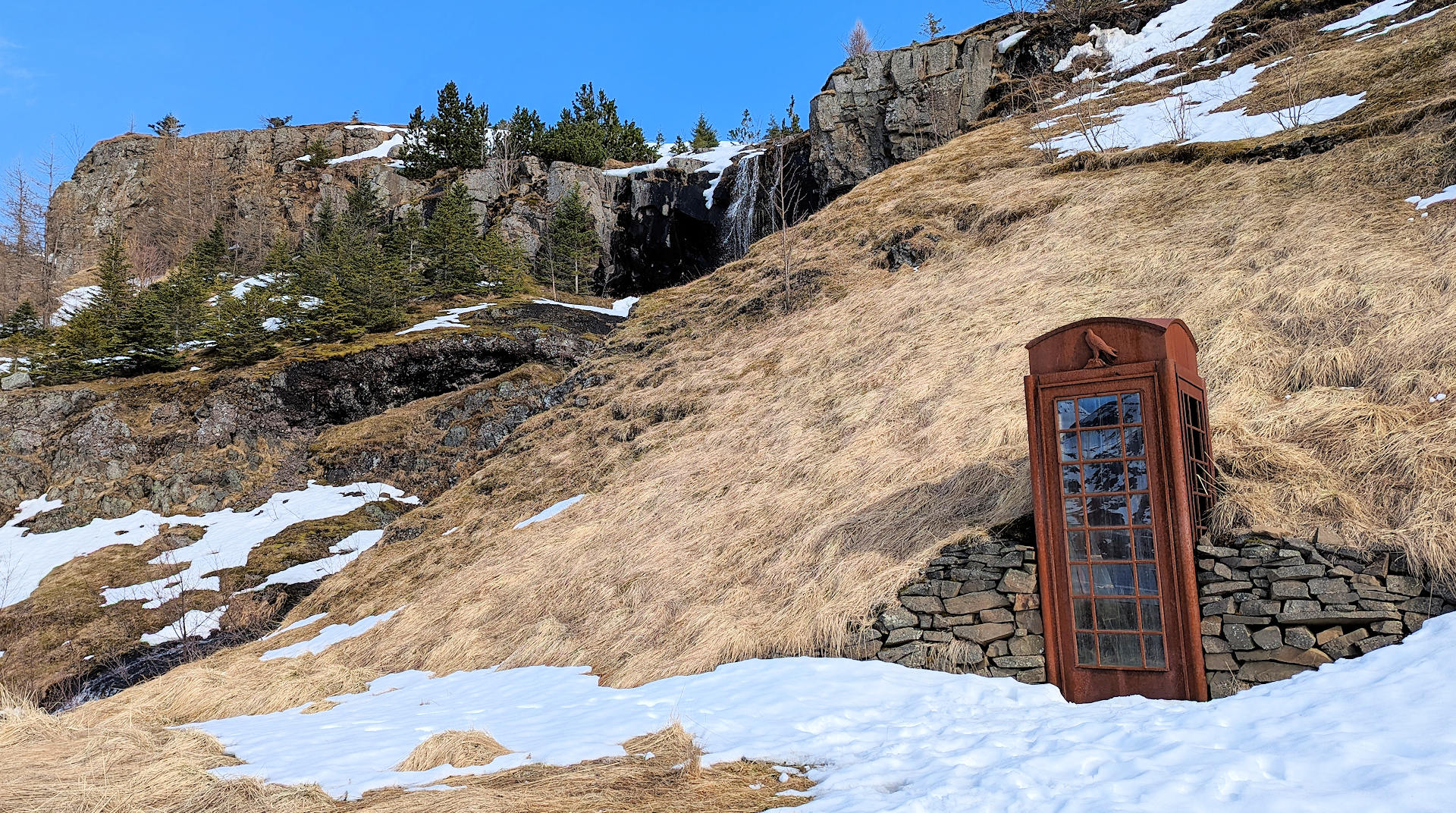 Stark verrostete Telefonzelle im Schnee in Seydisfjördur, Denkmal