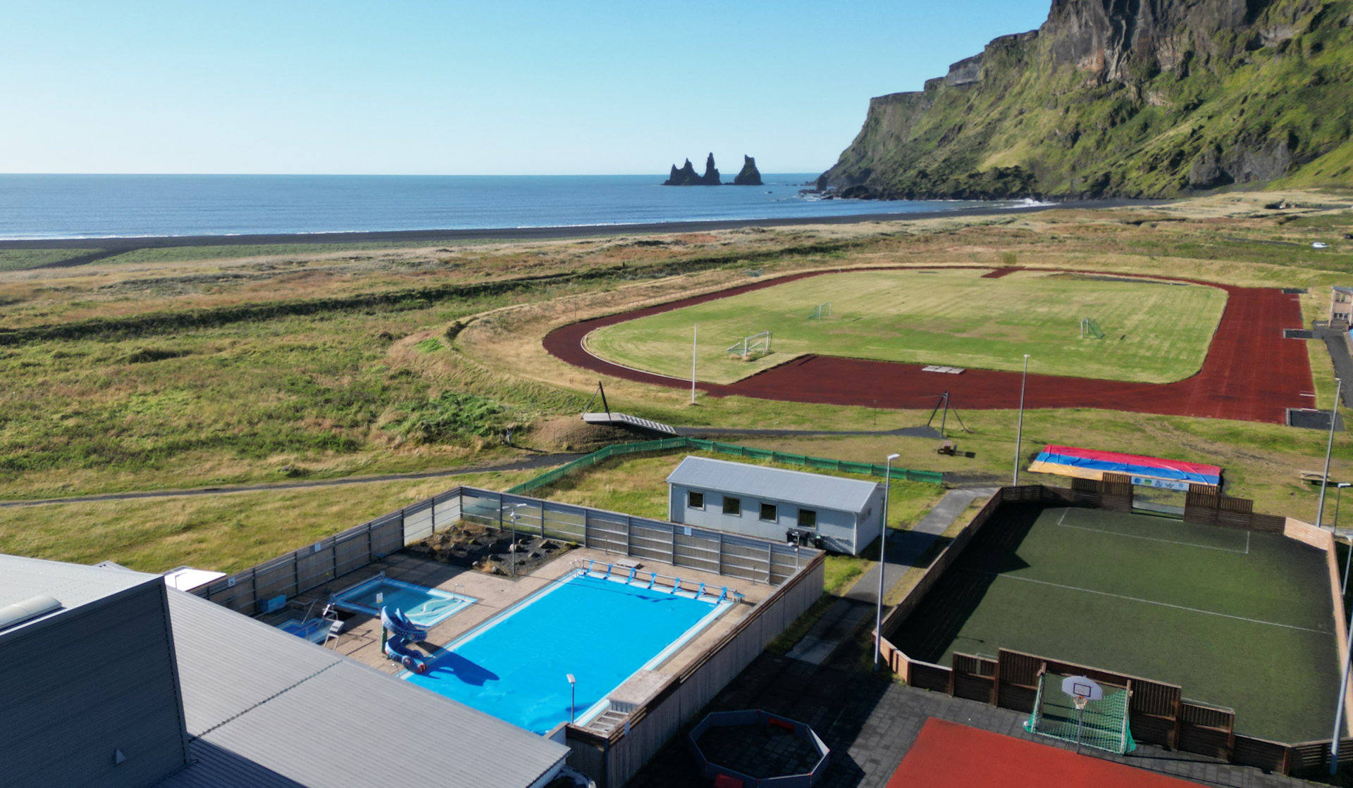 Luftbild Vik Island mit Bick auf das Schwimmbad und den schwarzen Strand