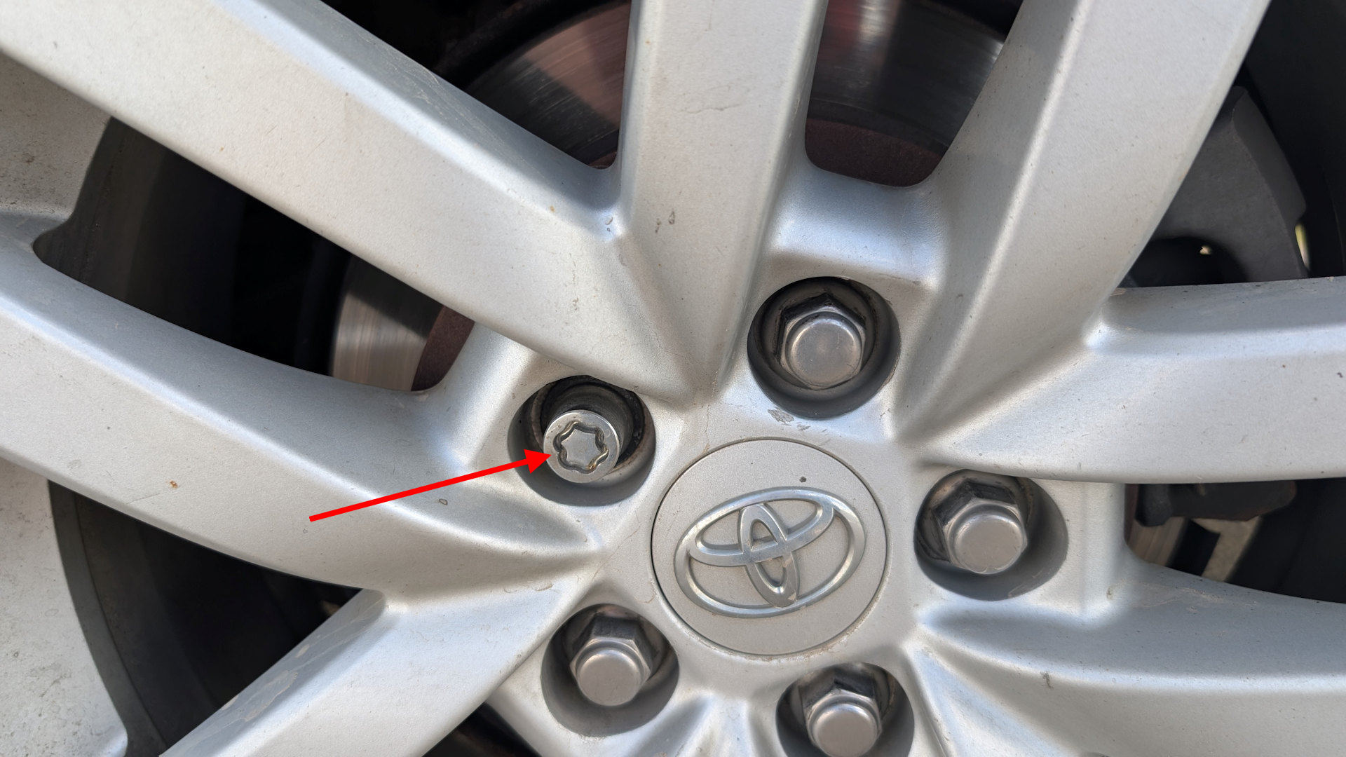 Roter Pfeil markiert eine ungewöhnlich aussehende Radmutter an einem PKW Rad