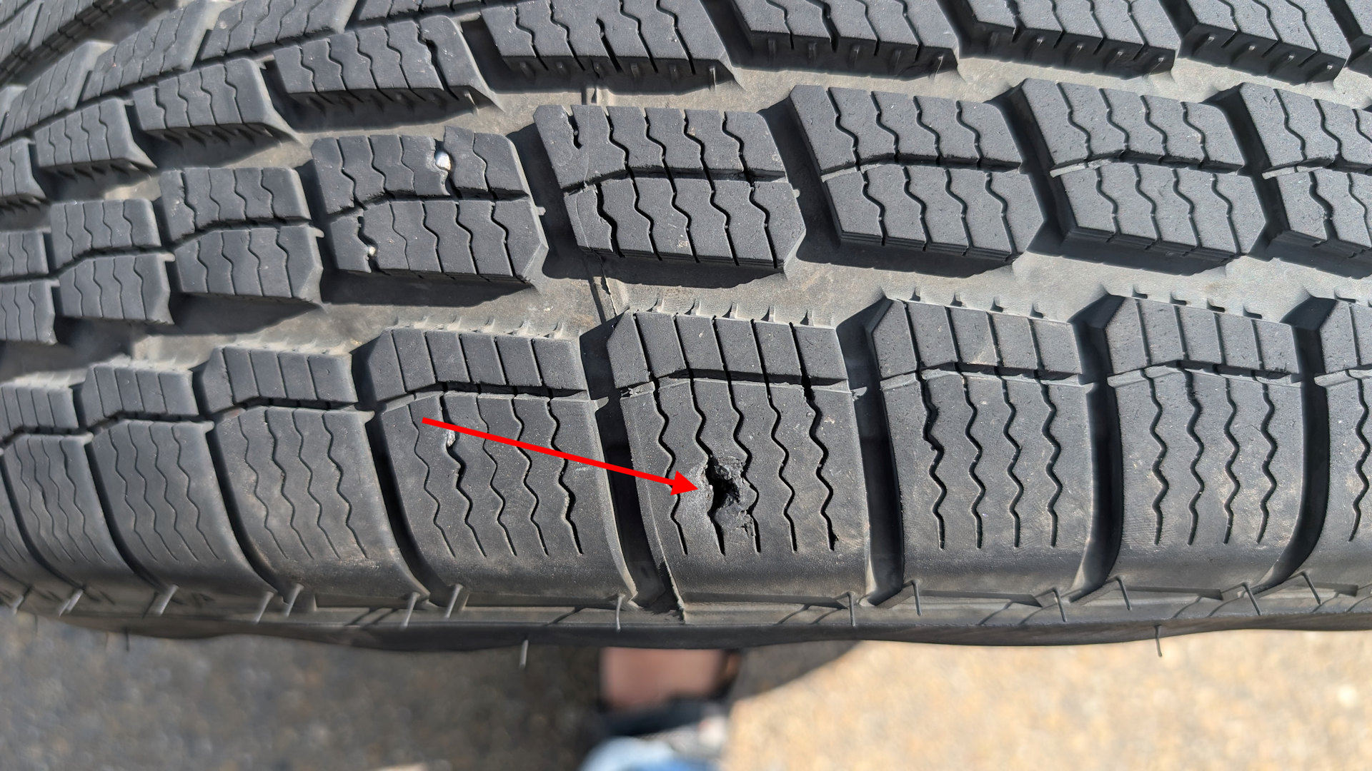 Roter Pfeil markiert einen Durchstich bei einem PKW Reifen