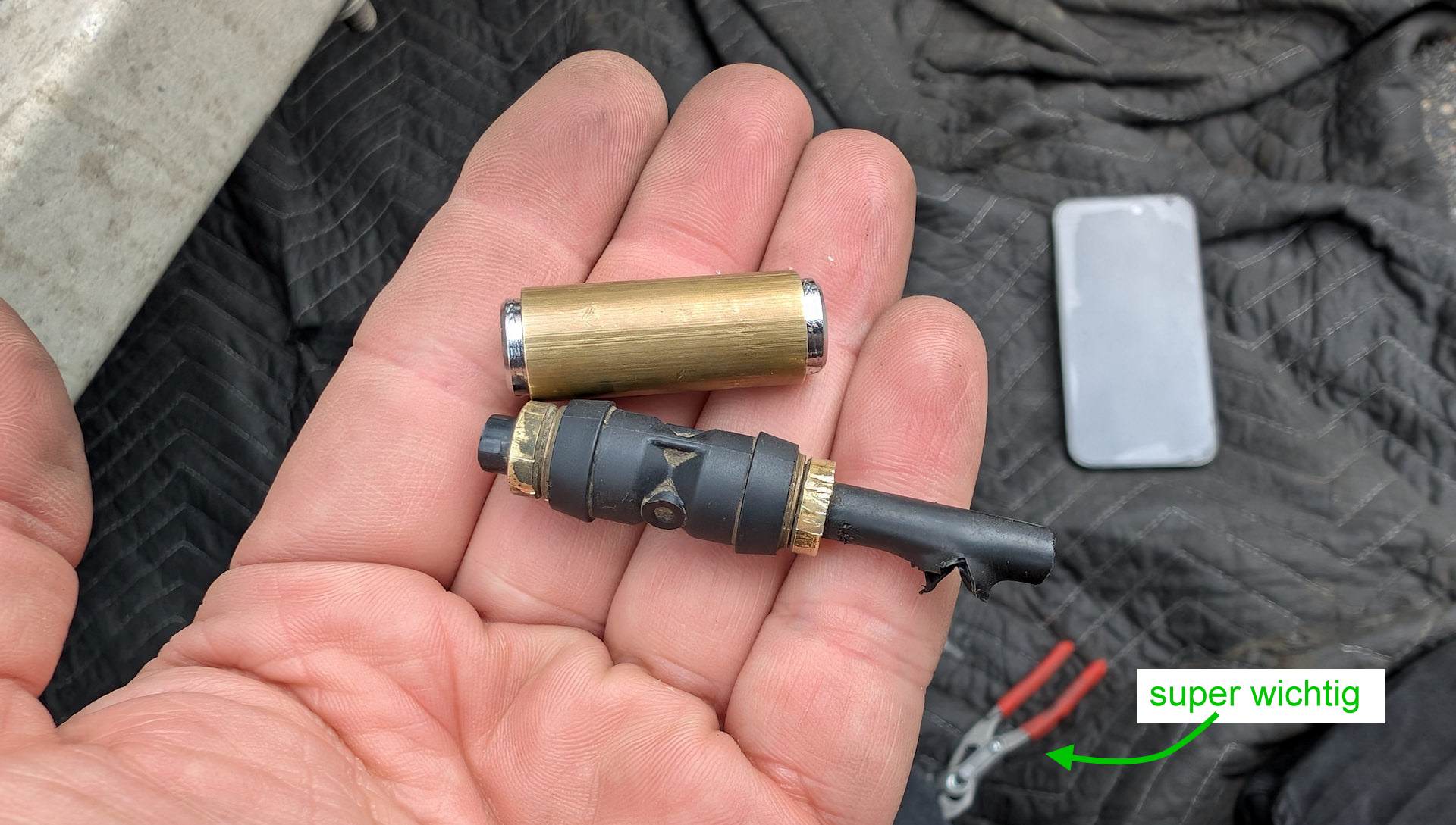 Zwei Druckluft Schnellverbinder aus einem LKW und eine kleine Zange im Hintergrund