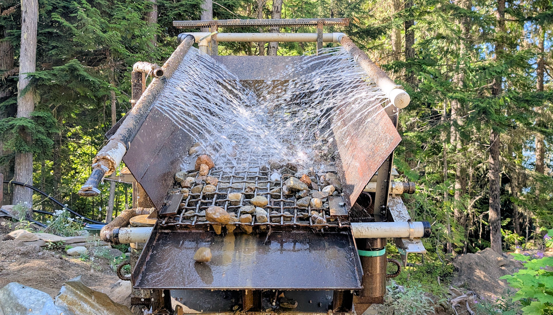 Waschbecken einer Goldwaschanlage wo Sand und Steine mit Wasser bespritzt werden
