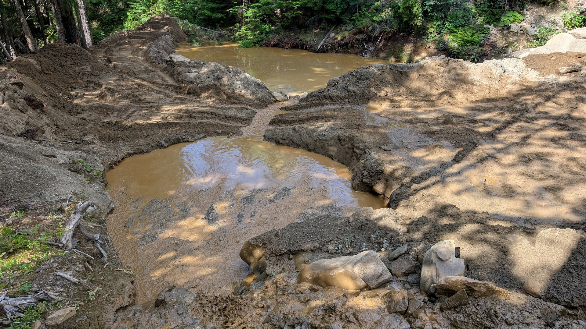 Zwei braune schlammige Absetzbecken in einer kleinen Goldmine