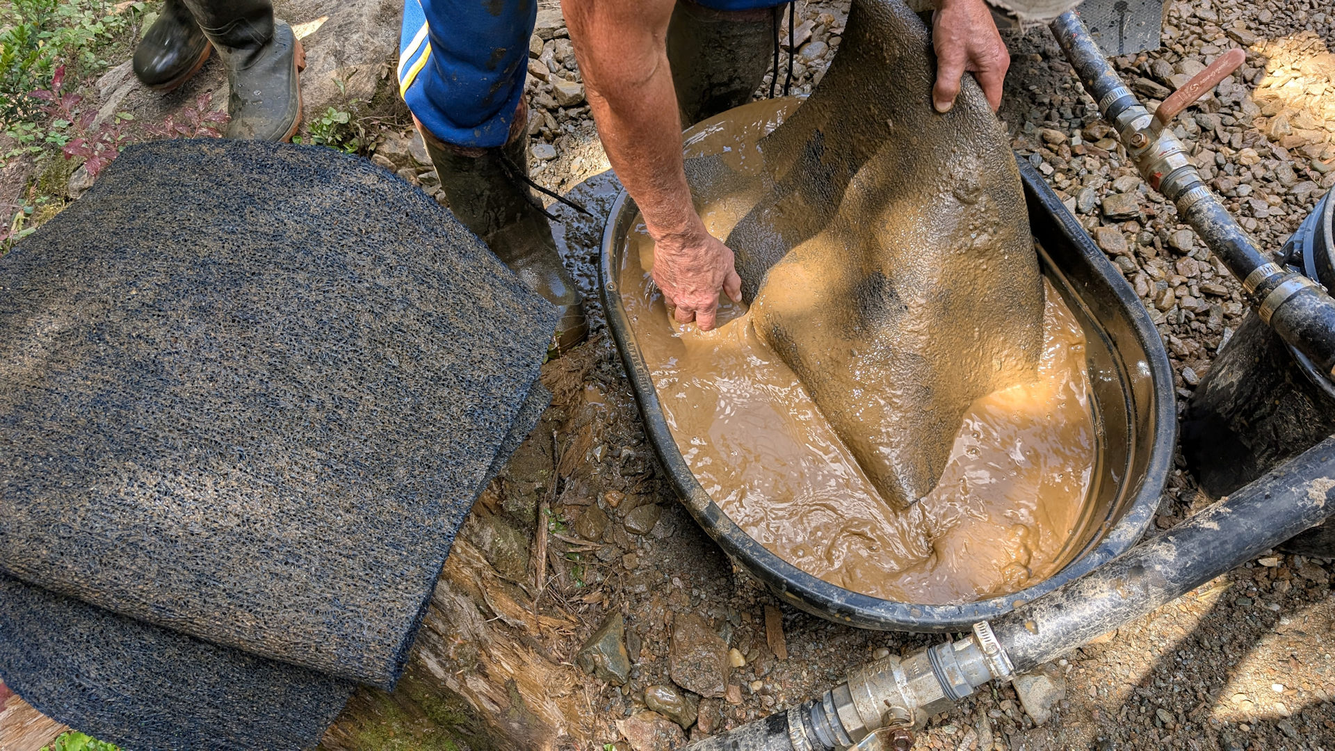 Filzmatte einer Goldwaschrinne wird in einem Bottich ausgewaschen