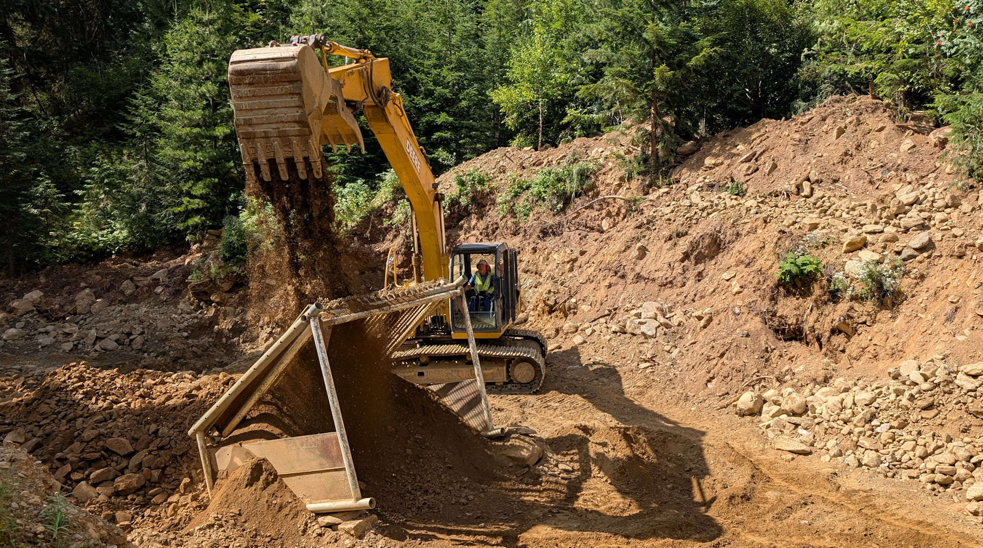 Ein Bagger lässt goldhaltigen Sand durch ein grosses Sieb fallen