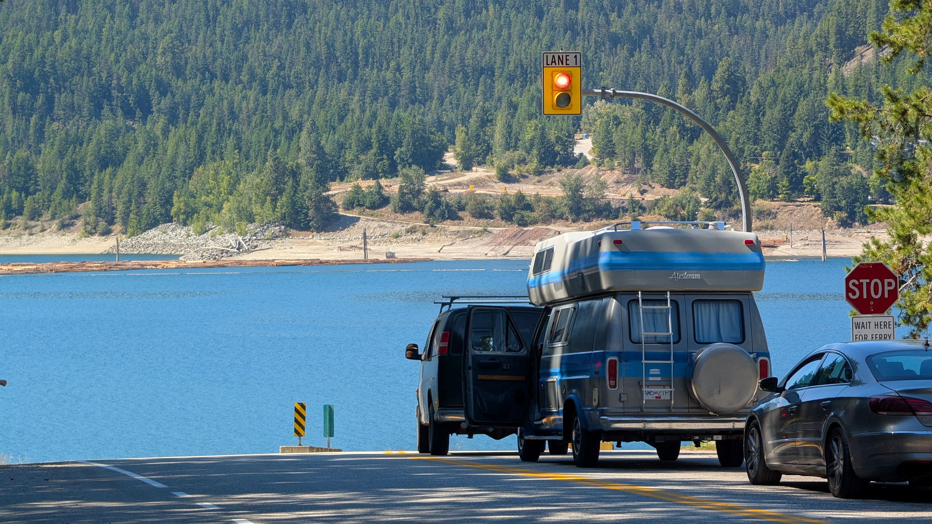 Autos warten am einem blauen Fluss mit Ampel auf eine Autofähre