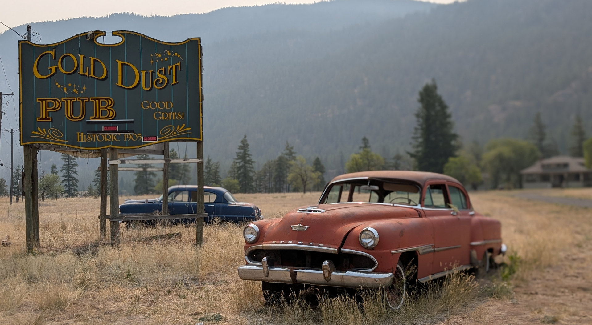 Ein roter und ein blauer Oldtimer parken neben einem Schild mit der Aufschrift Gold Dust Pub