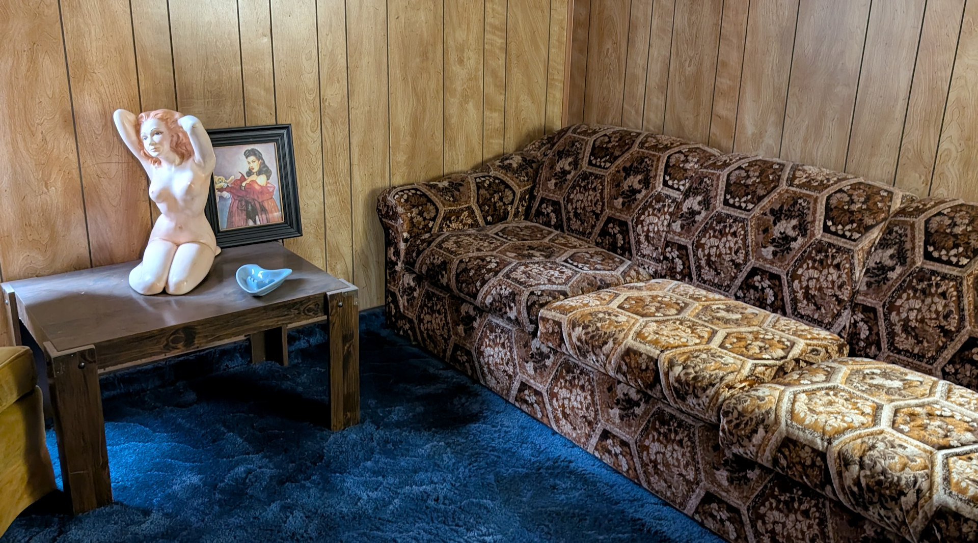 Helle Frauenbüste in einem Zimmer mit braunem Sofa und blauem Teppich