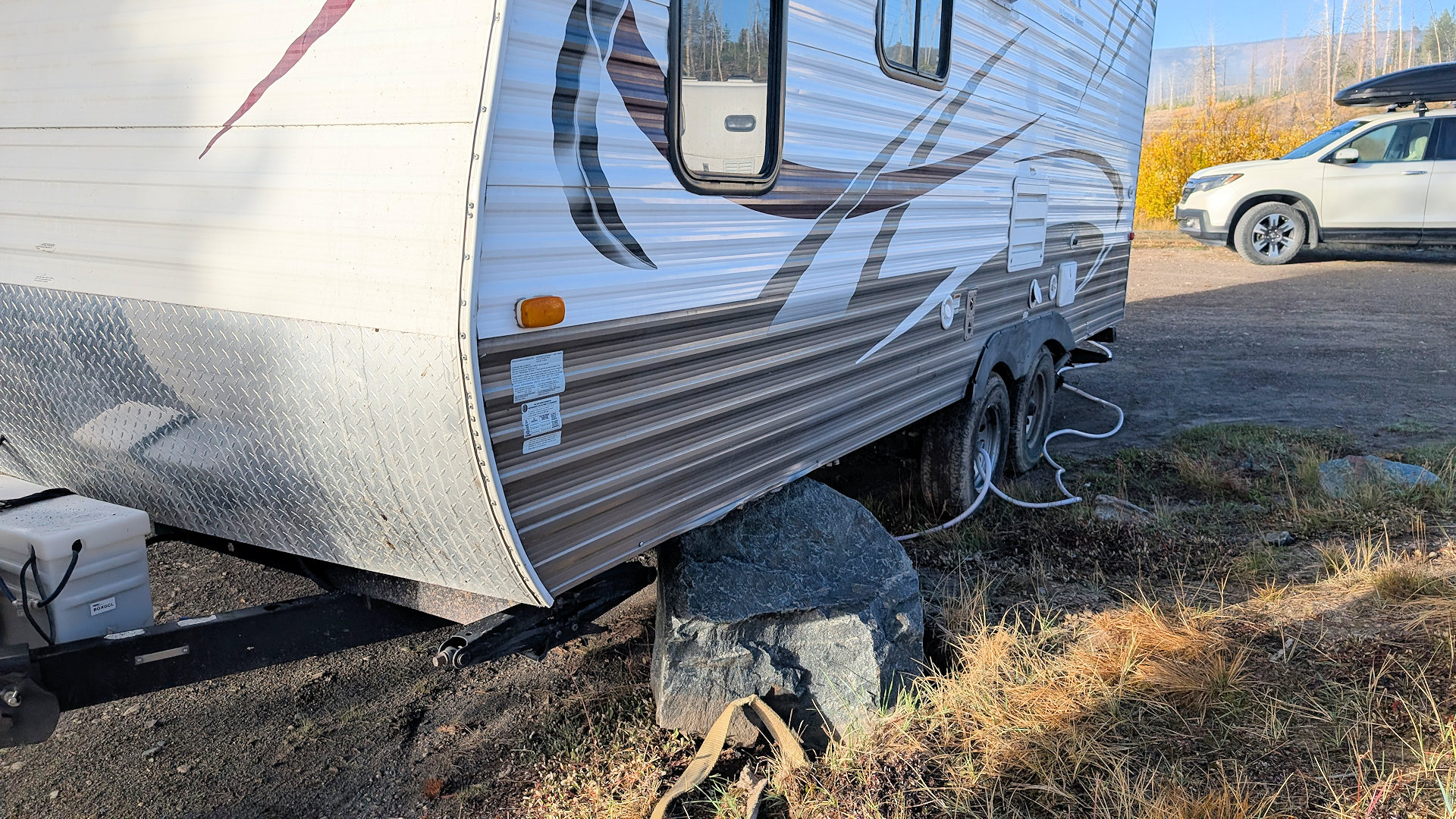 Ein Campinganhänger sitzt auf einem grossen Stein fest