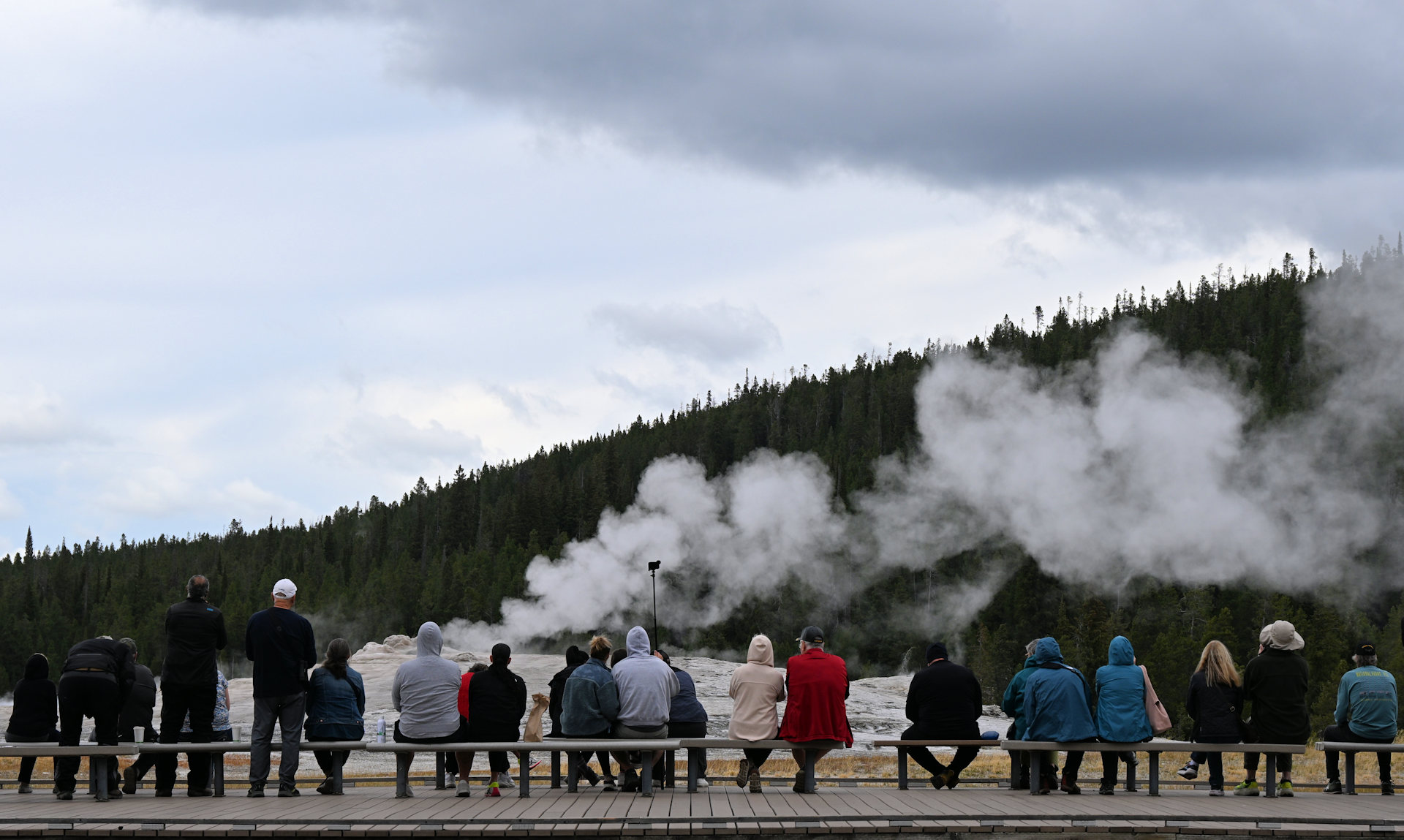 Besucher warten auf Sitzbänken auf den Ausbruch von einem Geysir