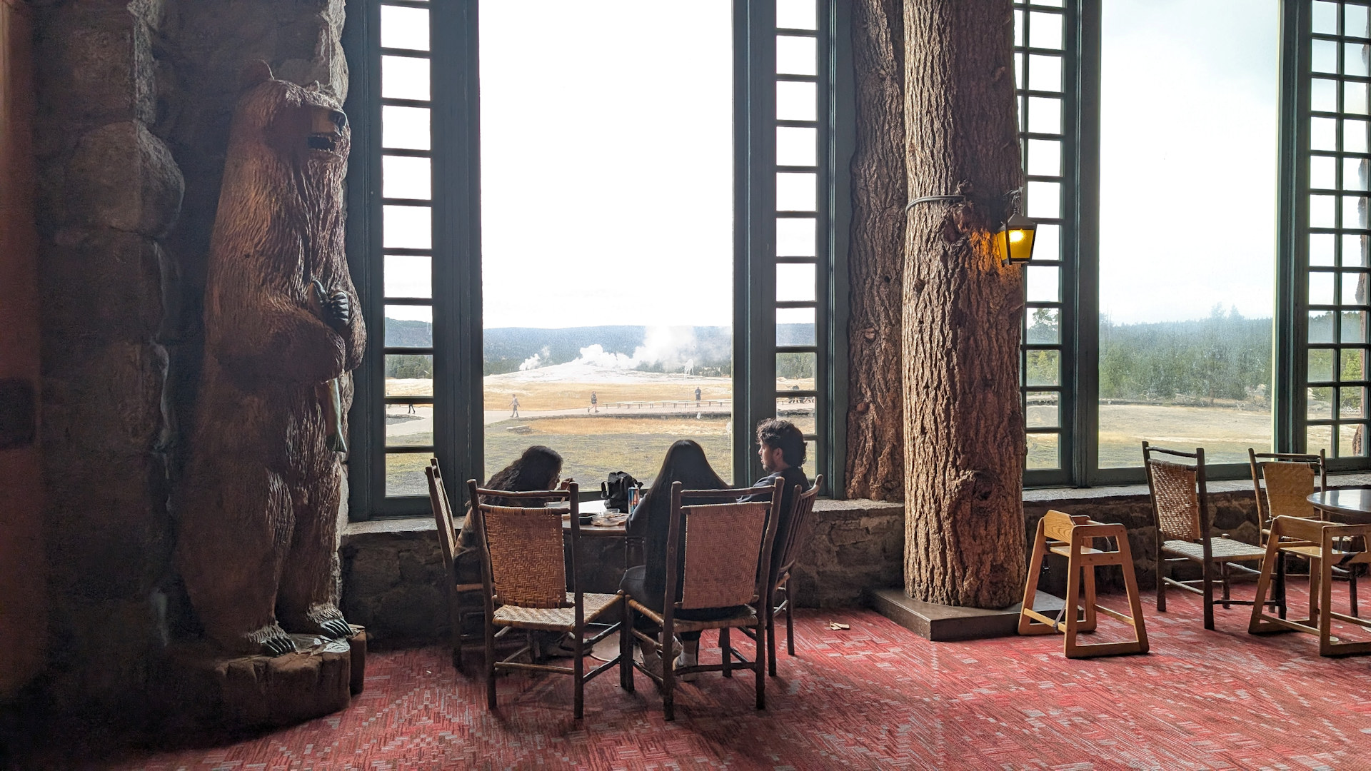 Speisesaal der Old Faithfull Lodge mit grossen Fenstern und Blick auf den Geysir