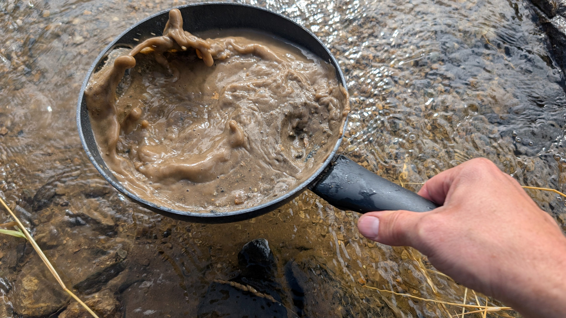 Sand Wasser Gemisch wird kräftig durchgeschüttelt. Fluss im Hintergrund