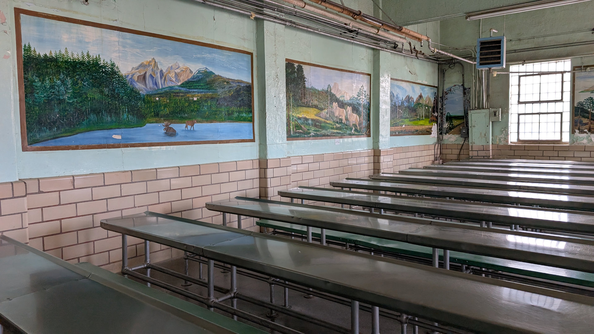 Kantine mit Metall Bänken und Landschaftsbildern im Frontier Prison Museum 