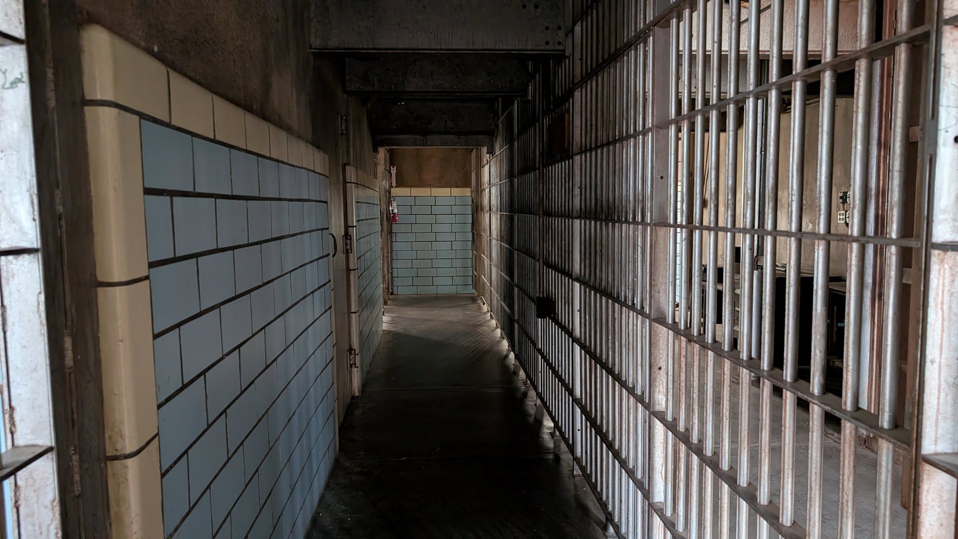 Dunkler Gefängnis Gang im  Wyoming Frontier Prison Museum in Rawlins mit Gitterstäben und gekachelter Wand 