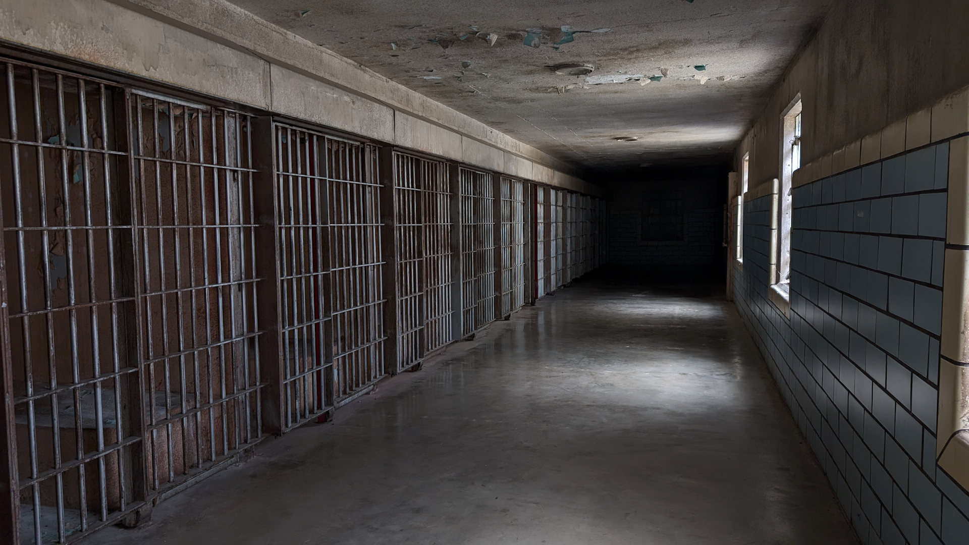 Vergitterte Gefängniszellen in einem dunklen Gang 