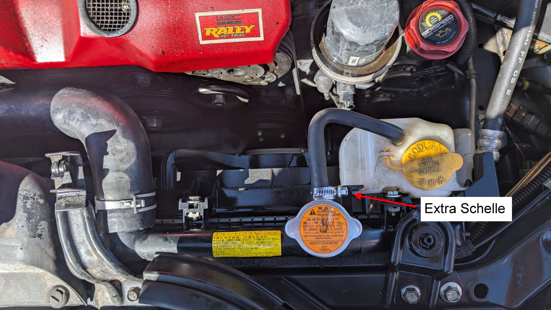 M;otorraum wo ein roter Pfeil auf eine zusätzlich angebrachte Schlauch Schnelle zeigt 