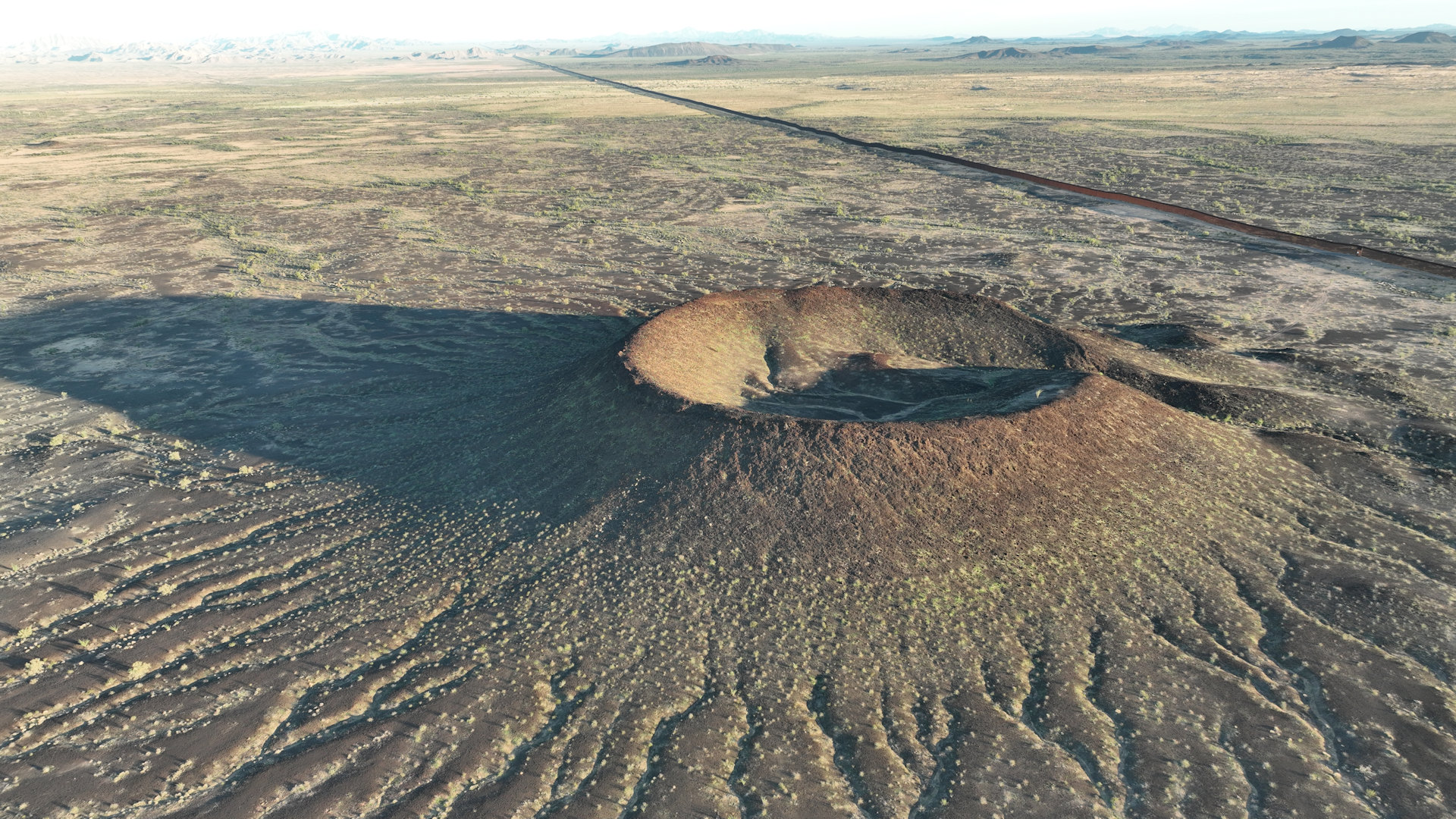 Vulkankegel in der Sonora Wüste mit Grenzzaun zu Mexiko im Hintergrund 