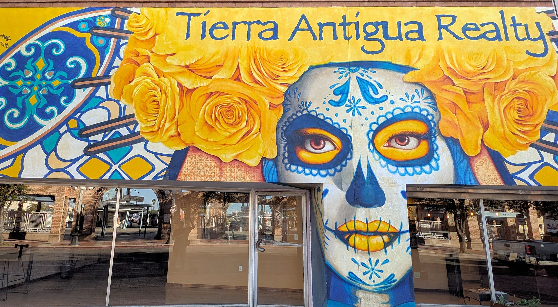 Tierra Antigua Realty Wandbild mit einer Frau die gelbe Rosen als Kopfschmuck trägt.