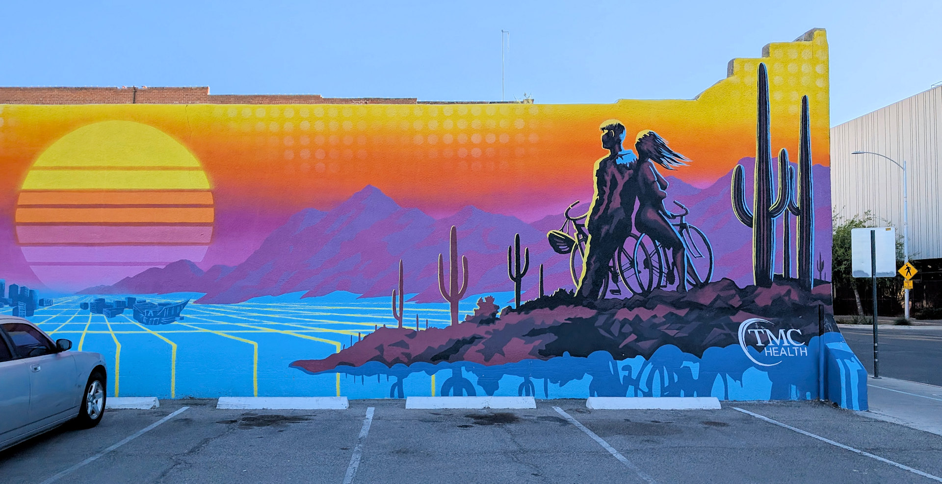 El Tour de Tucson Wandbild von Joe Pagnac mit zwei Radfahrern vor einer computergenerieten Wüstenlandschaft