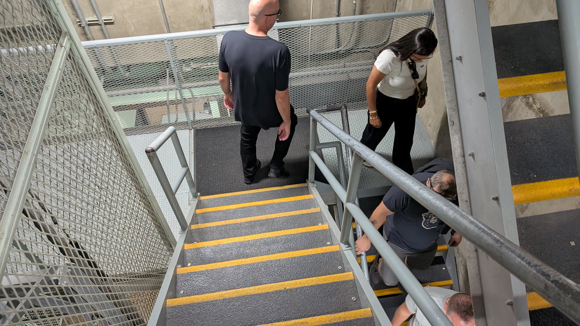 Vier Personen gehen eine Treppe mit gelb markierten Trittstufen hinunter 