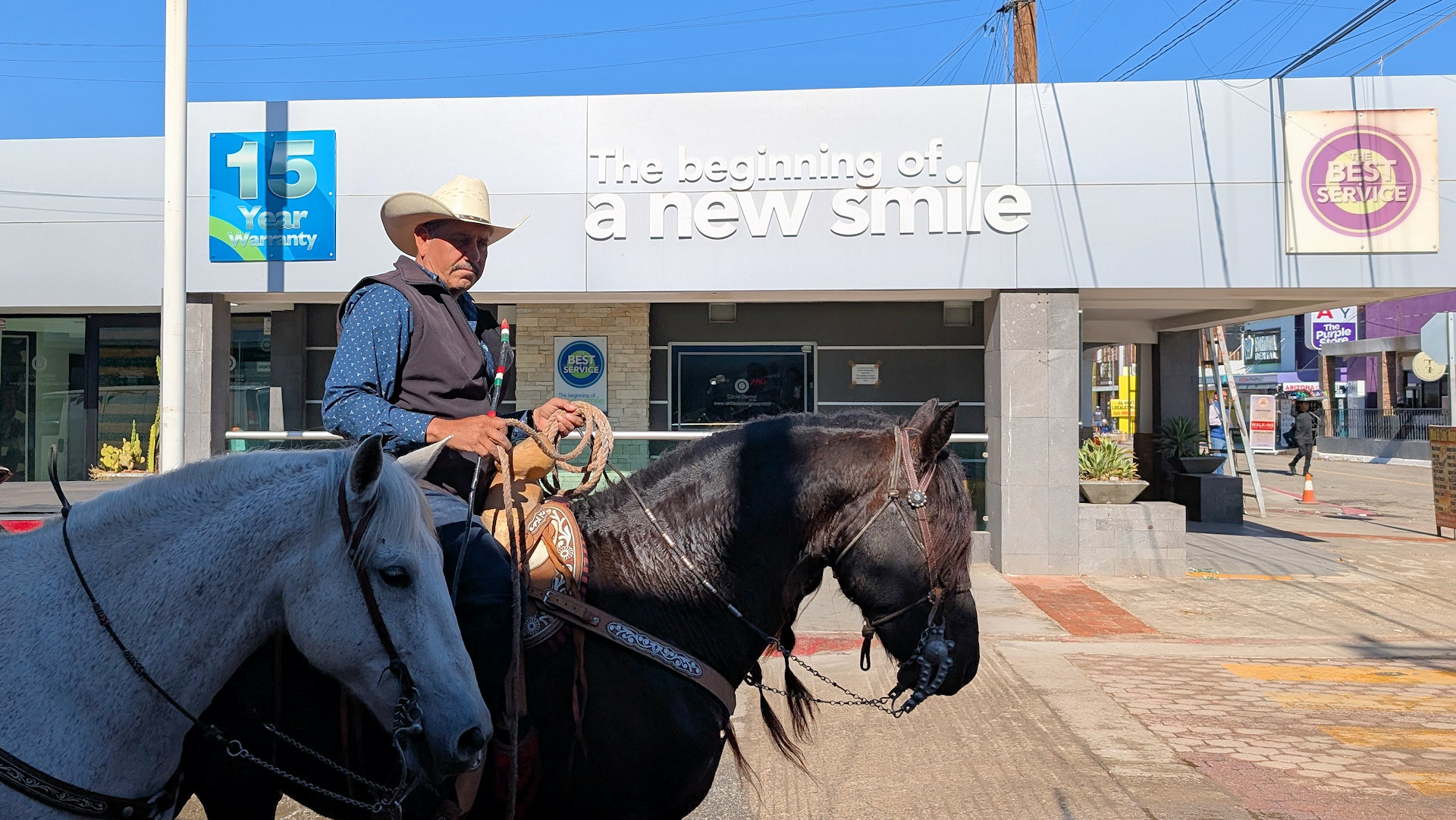 Ein Mann mit zwei Pferden reitet in Nuevo Algodones an einer Zahnarzt Klinik vorbei 