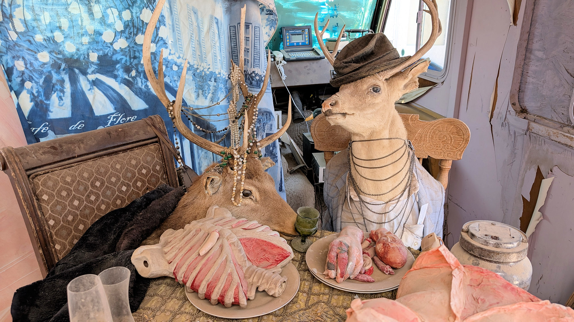 Zwei Hirsche sitzen an einem mit menschlichen Teilen gedeckten Tisch als Kunstwerk in Slab City