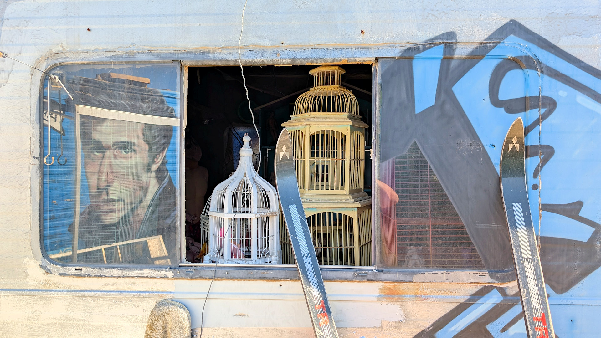 Fenster eines Wohnmobils mit zwei Vogelkäfigen