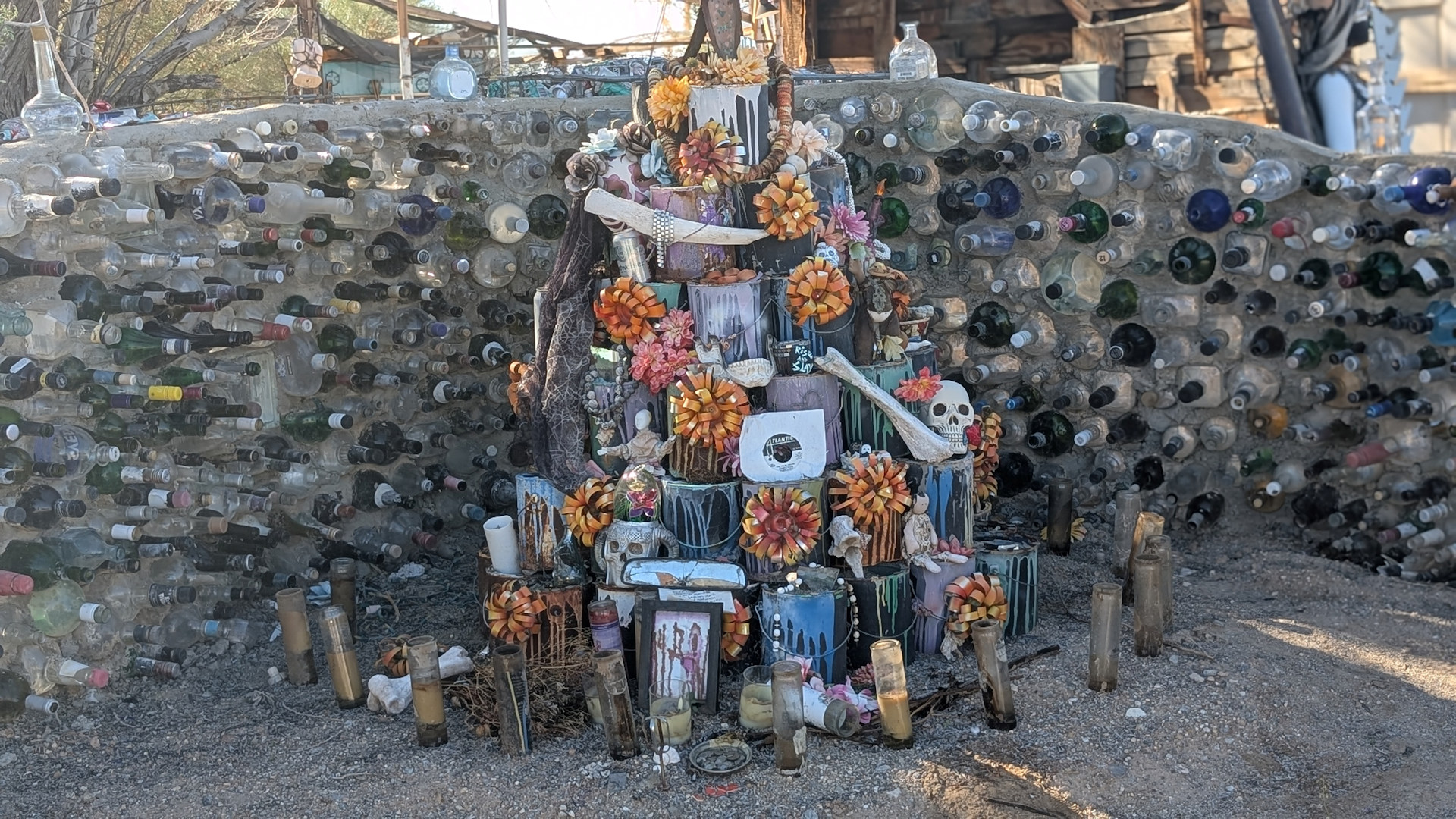 Altar aus Blumen vor einer Wand aus Flaschen in Slab City Kalifornien