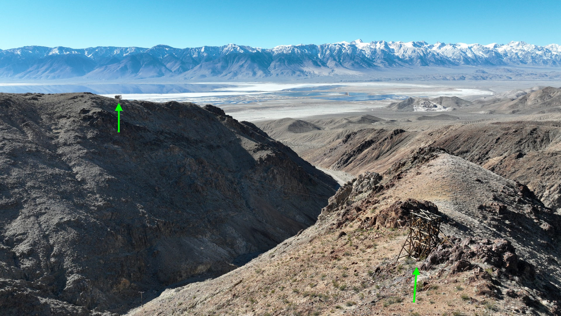 Panorama Blick auf die Berge in der Nähe von Cerro Gordo. Zwei grüne Pfeile markieren Seilbahn Türme aus Holz.