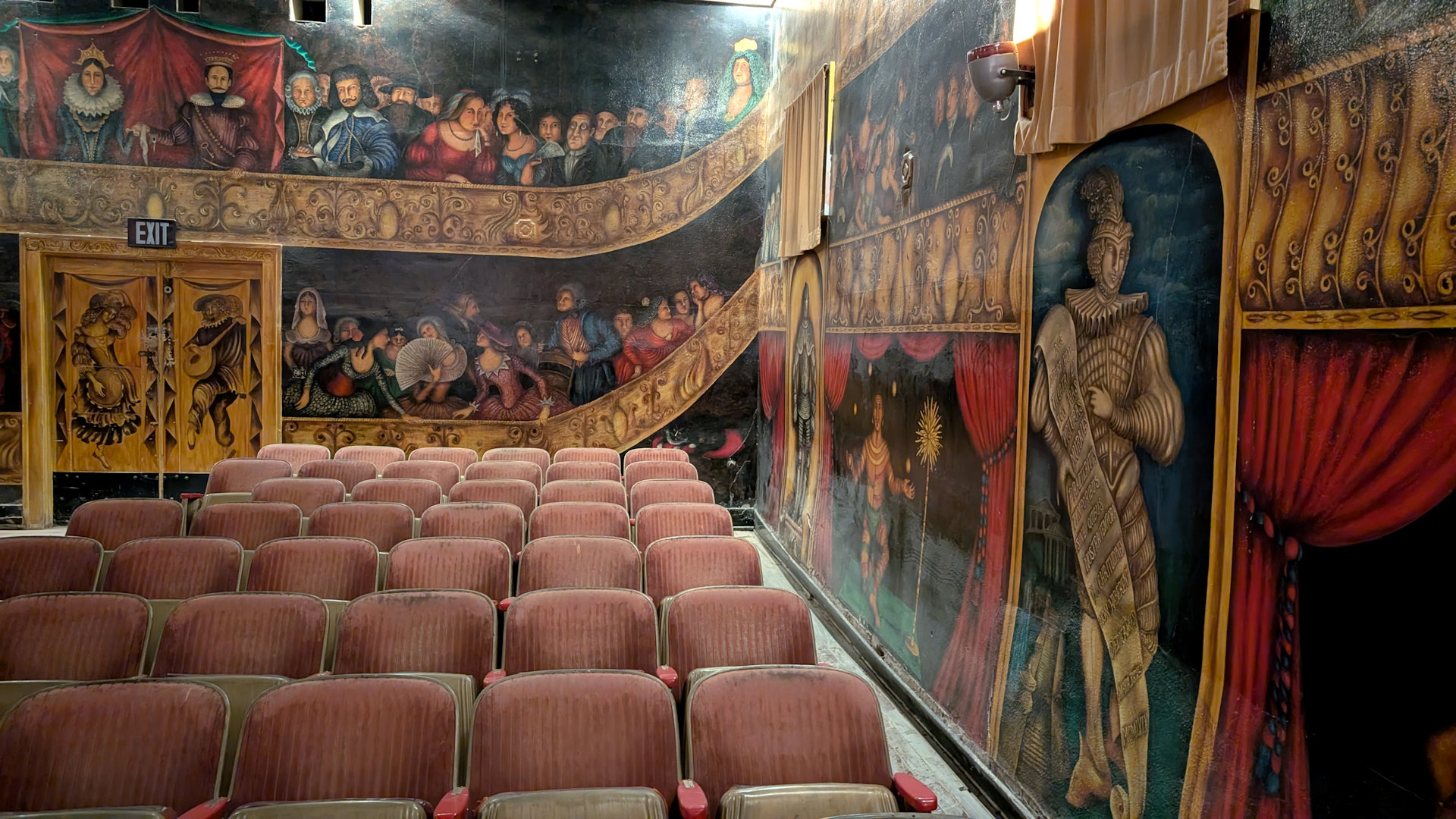 Innenraum der Amargosa Opera Death Valley Junction mit Stühlen und bunten Wandbildern 