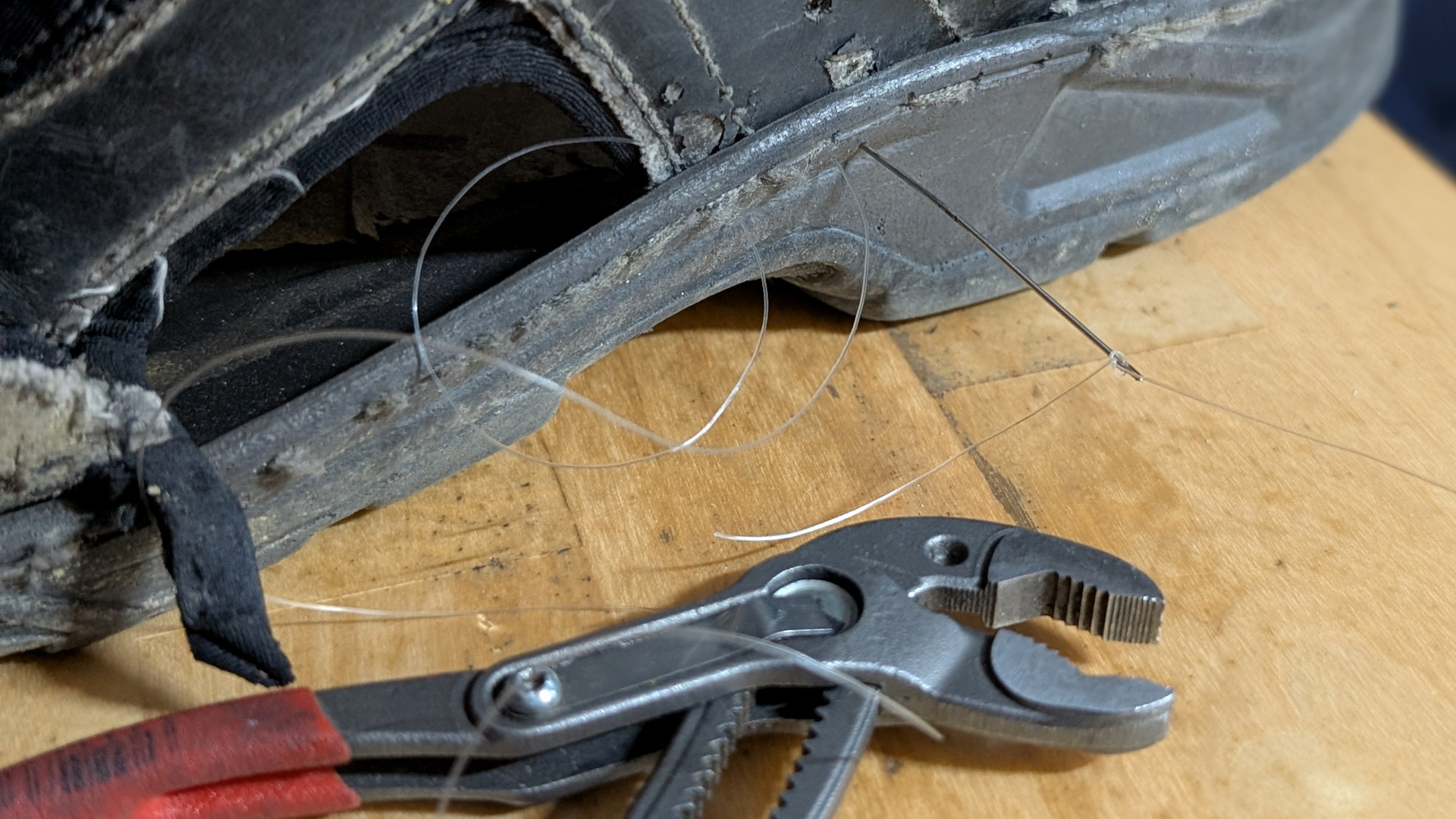 Zange als Hilfe um eine Sandale mit Nylonfaden zu reparieren