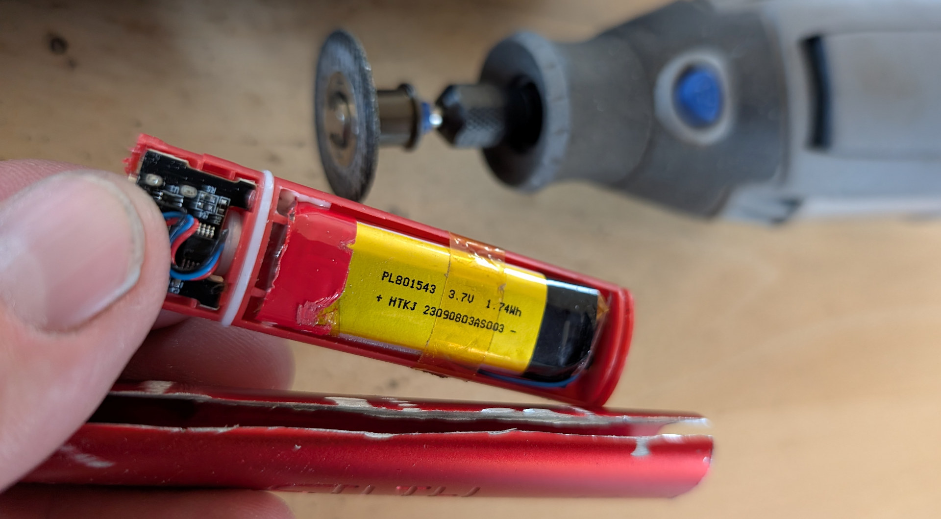 geöffnete eZigarette mit sichtbarem 3,7 Volt Lithium Akku und Dremel im Hintergrund