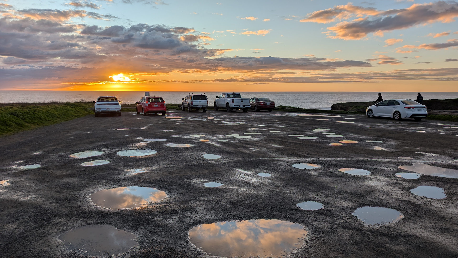 Wolken spiegeln sich in Pfützen auf einem Küstenparkplatz bei Mendocino