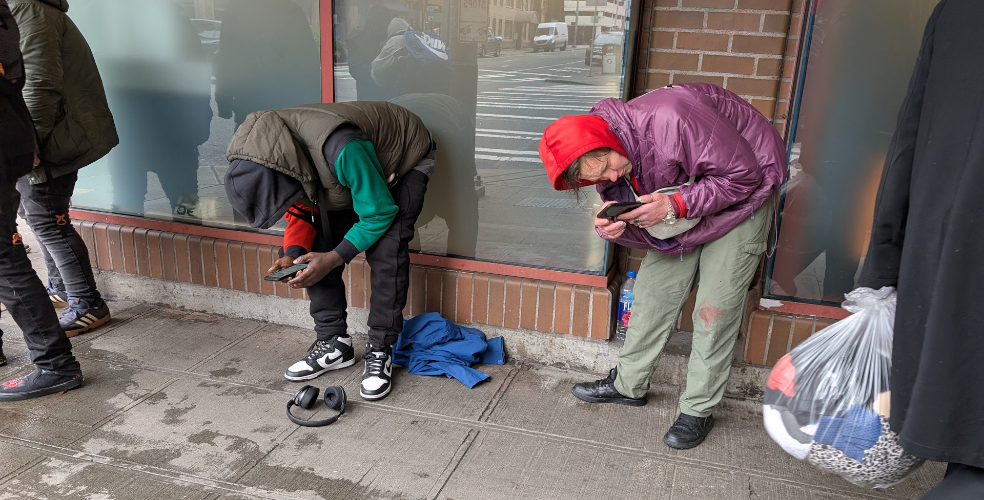Zwei krumm stehende Fentanly Konsumenten spielen am Handy