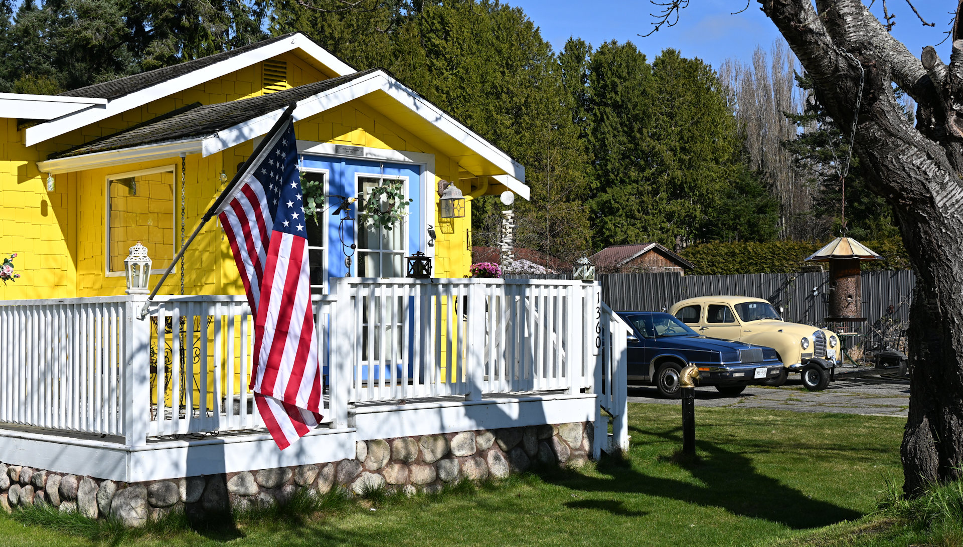 Gelben Ferienhaus in Point Roberts mit amerikanischer Flagge und zwei Oldtimern 