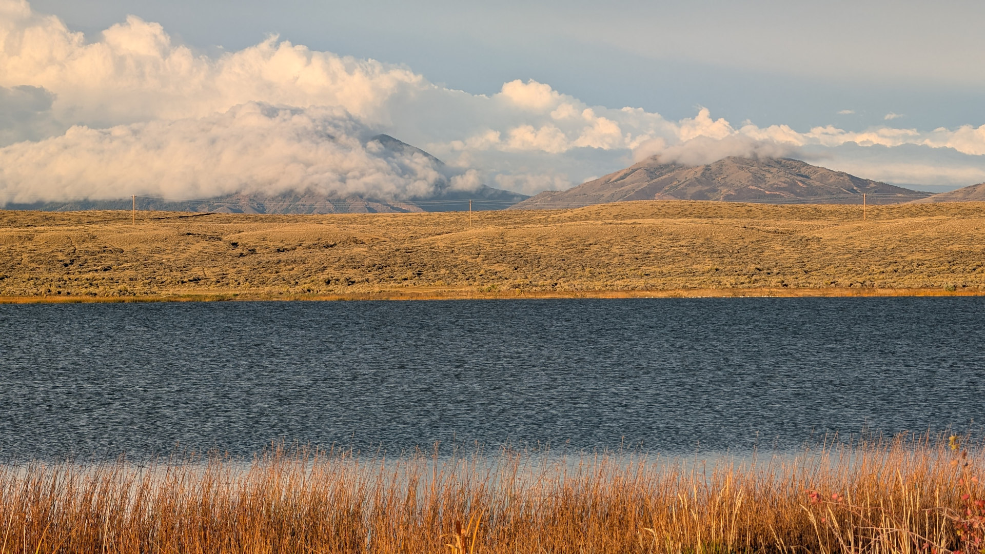 Blauer See und gelbliche Hügel mit Wolken