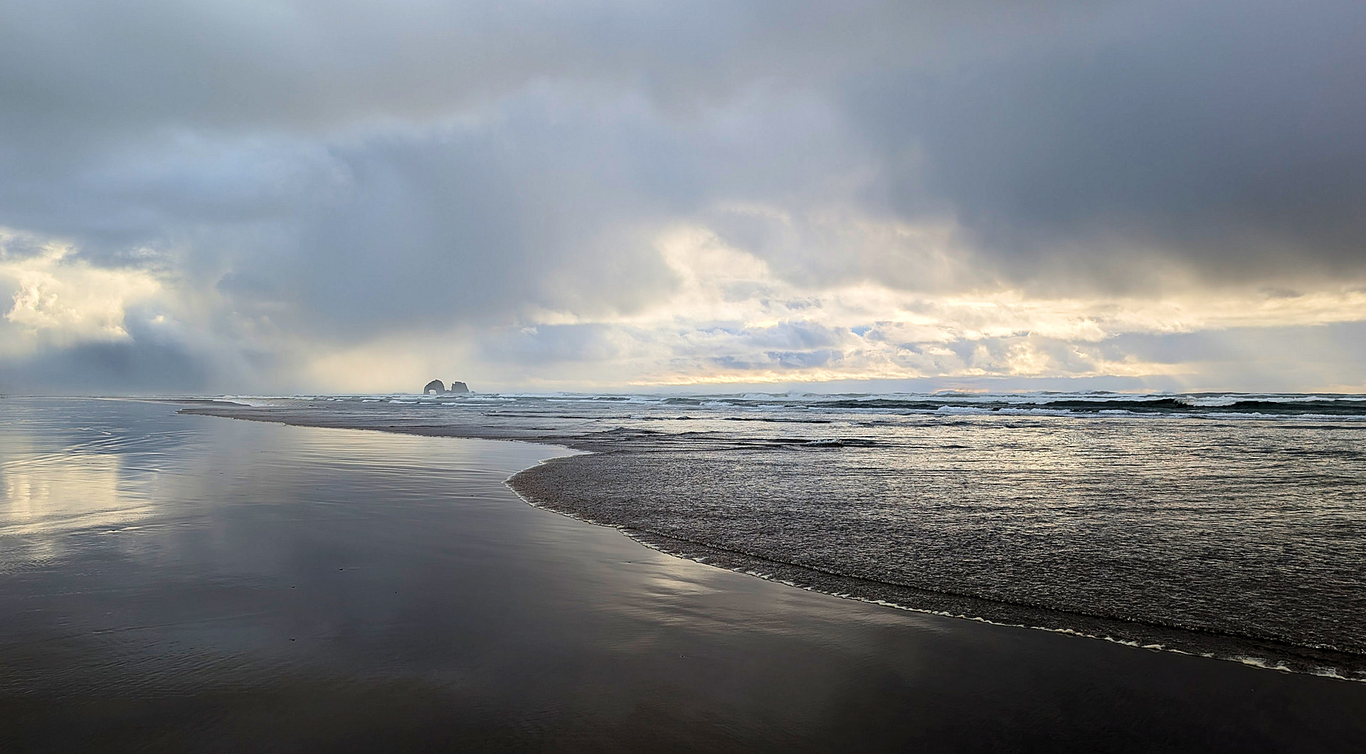 Küste Oregons mit salzwasserüberspültem Strand und dunklen Wolken